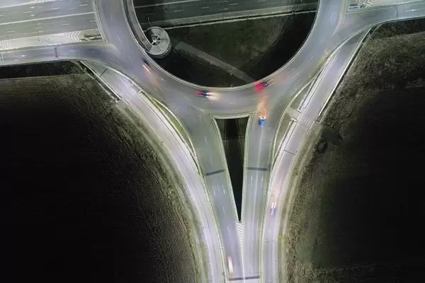 Drohnenbild zeigt Autos im Straßenverkehr bei Nacht, im großen Verkehrskreisel