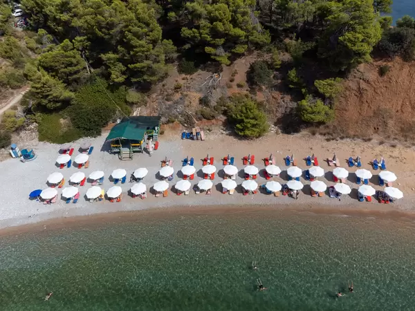 Drone image of Kokkinokastro beach with rows of white parasols and sunbeds on the Greek island of Alonnisos