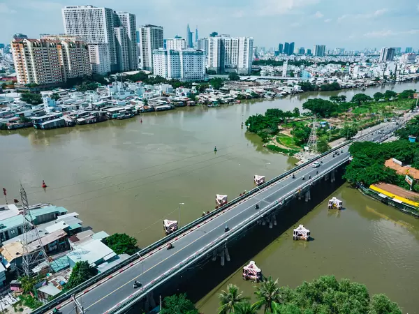 Drone Photo of a Bridge and Power Lines over Saigon River with Apartment Buildings, Bitexco Financial Tower and Landmark 81 in the Background in Ho Chi Minh City, Vietnam