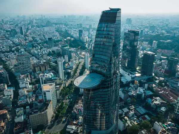 Drone Photo of Bitexco Financial Tower with cantilevered Helipad on the 55th Floor in the Center of District 1 with Public Parks, Constructions and Buildings in the Background in Ho Chi Minh City, Vietnam