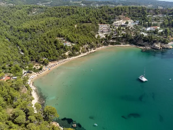 Drone photo of the breathtaking bay of Chrisi Milia surrounded by green hills with tourist accommodation