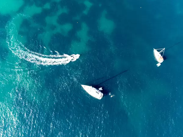 Drone photo of three boats and some people swimming in the crystal clear waters of Skopelos, Greece