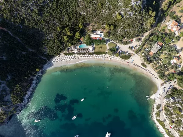 Drone photography in Greece: the bay of Limnonari with beach, swimming pool, pine forest and boats