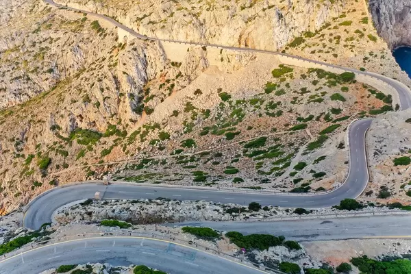 Drone shot of the snake road climbing up to the top of the rocky Cap de Formentor headland in Majorca