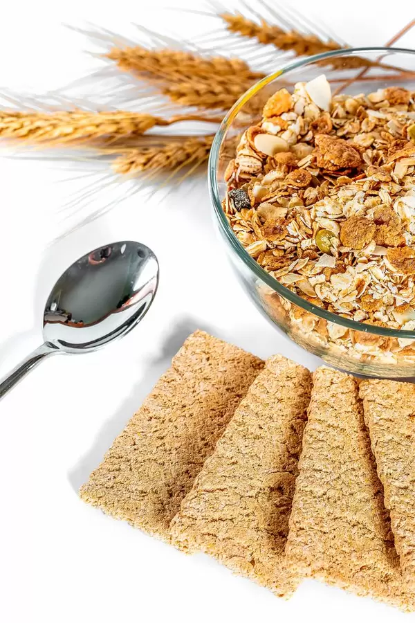 dry briquettes of dietary bread with a bowl of porridge and wheat spikelets on a white table with a spoon