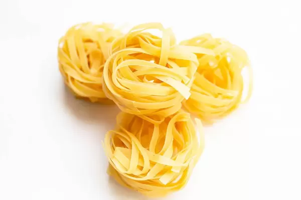 Dry tagliatelle pasta on white background  Flip 2019