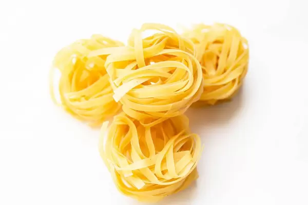 Dry tagliatelle pasta on white background.jpg