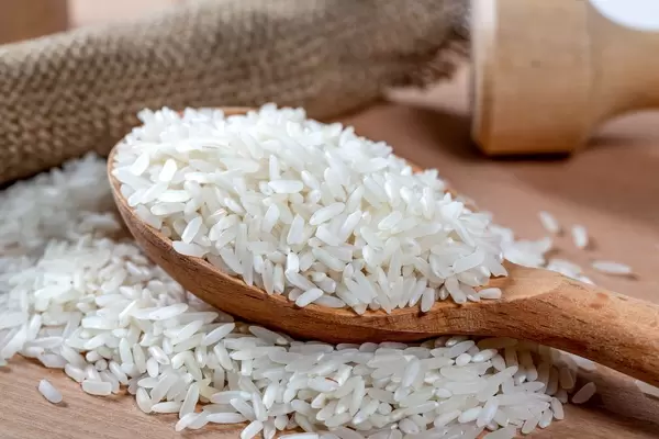 Dry white long rice in wooden spoon