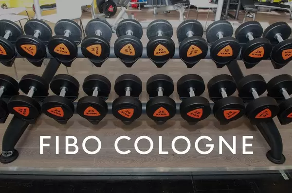 Dumbbells in various weight classes on a dumbbell rack in the gym, next to the picture title Fibo Cologne