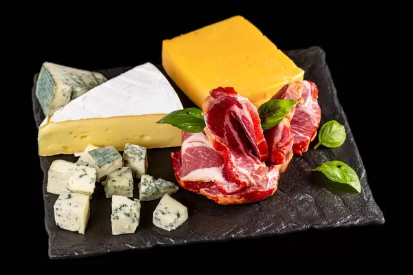 Dutch cheese, brie cheese and dor blue cheese with smoked ham on a black stone tray