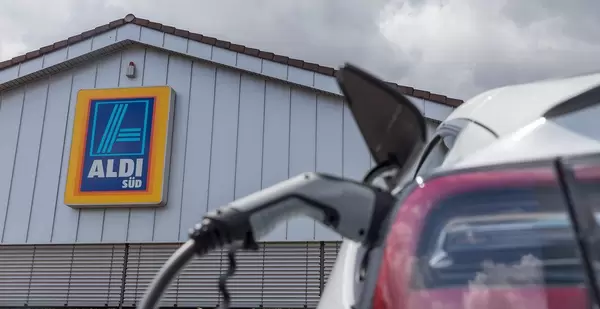 E-Mobility: Tesla Model 3 with a type 2 charger plug, recharges solar energy in front of the Aldi-Süd supermarket in Germany
