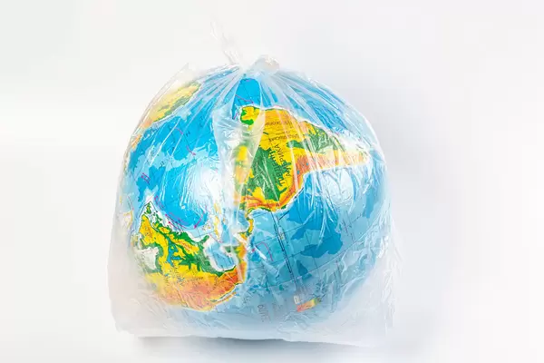 Earth in polyethylene plastic disposable package on white background. Concept pollution of environment with polyethylene plastic waste, ecological problems