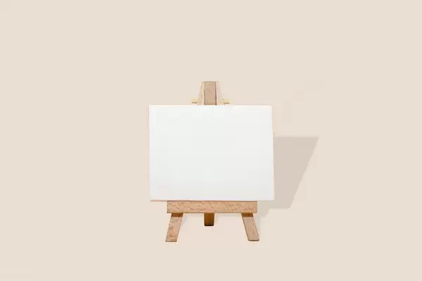 Easel with blank canvas on cream background
