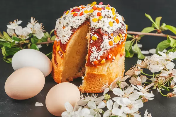 Easter cake, eggs and spring flowers on black background