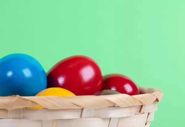 Easter eggs in a basket on green background