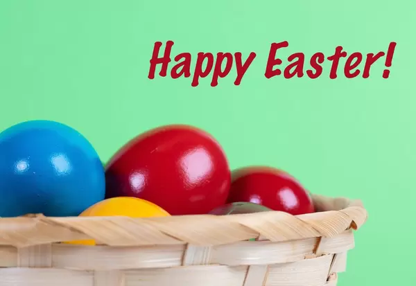 Easter eggs in a basket with Happy Easter text on green background