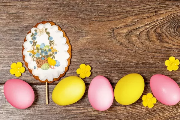 Easter gingerbread and multicolored chicken eggs on a wooden background, top view