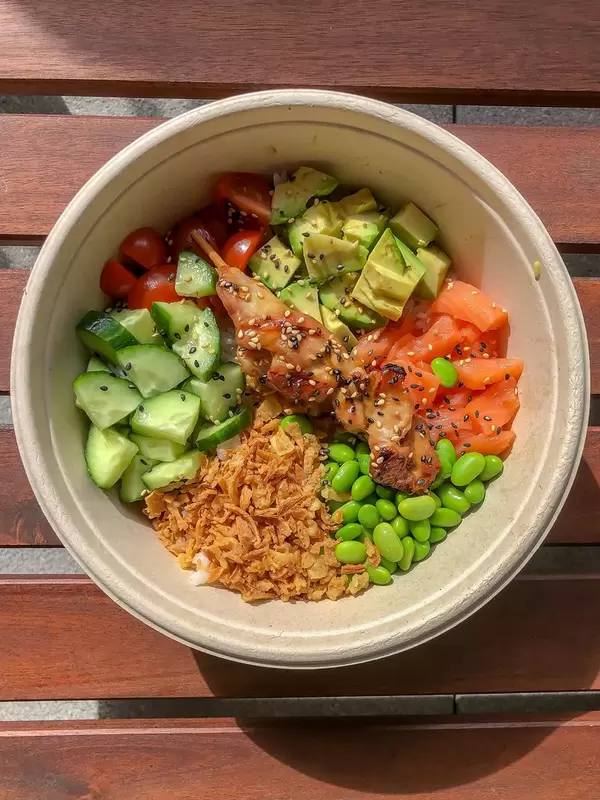 Eat Simple Tagesmenü Surf & Turf Bowl mit Chicken Teriyaki, Sushi Reis, gewürfelter Lachs, Ackerbohnen und Röstzwiebeln in einer Schale
