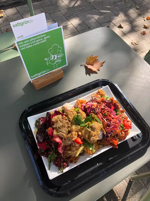 Eating at an outdoor table from a rich plate at the Sattgrün vegan buffet in Cologne
