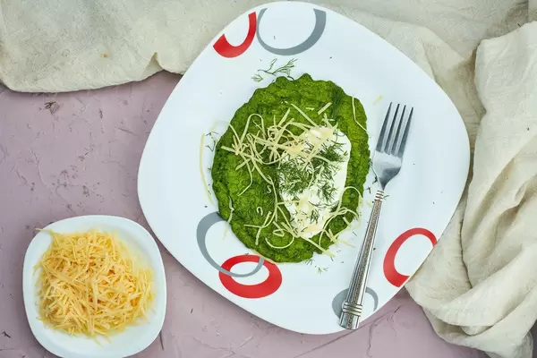 Eating spinach waffles with sour cream and shredded cheese