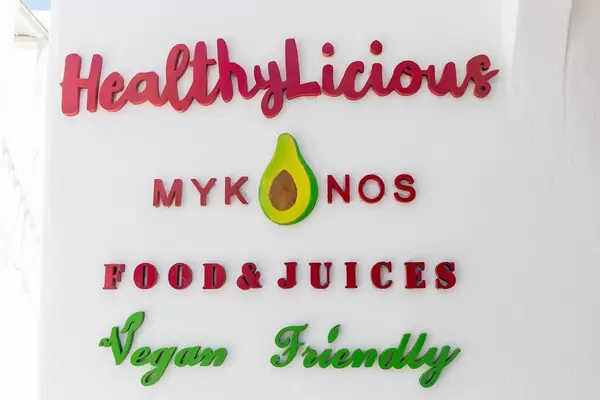 Eating vegan in Mykonos: HealthyLicious Food & Juices restaurant. Sign on white wall