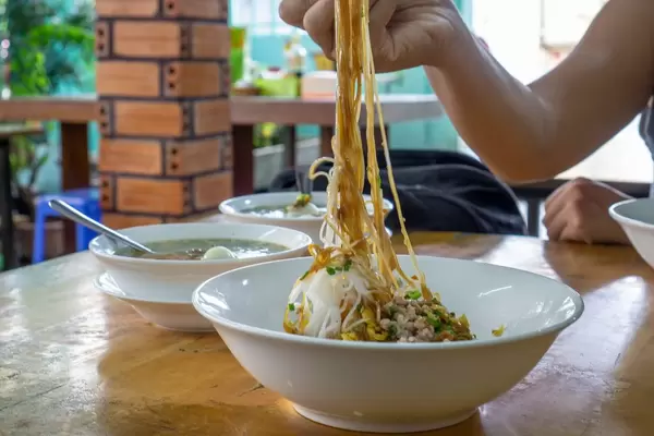 Eating Vietnamese Noodles with Pork in a Breakfast Restaurant in Saigon