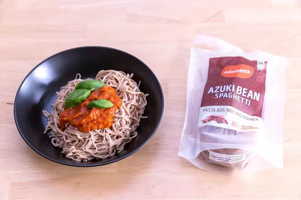 Edamama Bio-Spaghetti made from Azuki Beans with Tomatensauce and basil leaves on black plate and packaging