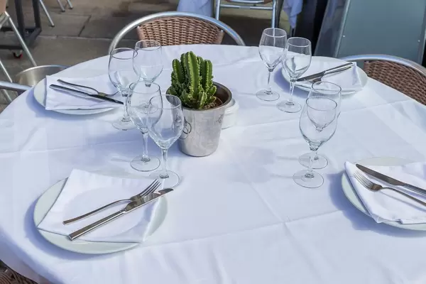 Edel gedeckter Tisch mit weißer Tischdecke, Servietten, Besteck, Gläsern und einem Kaktus in einem Restaurant in Barcelona, Spanien