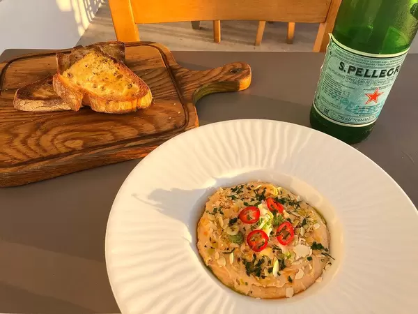 Eggplant spread dip with smoked eggplants and tahini, next to sliced grilled bread on a wooden board
