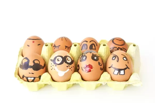 Eggs with funny faces in the packaging on white background symbolising happy easter