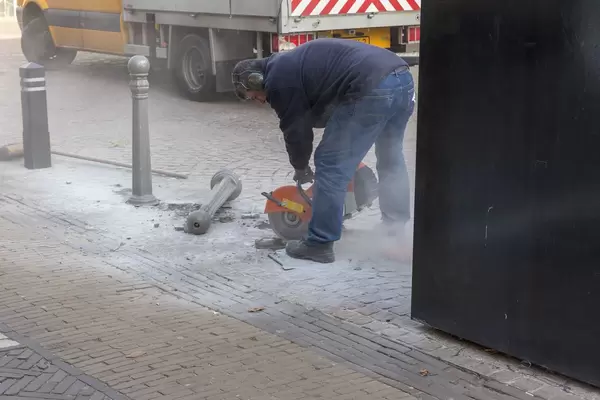 Ein Bauarbeiter schneidet mit der Steinsäge eine Auskerbung in den Gehweg
