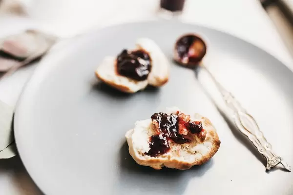 Ein Brötchen mit Marmelade auf einem Teller mit einem Löffel