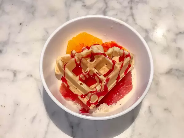 Ein Dessert aus einer belgischen Waffel auf einer Scheibe Blutorange mit Vanille-Creme und rotem Topping