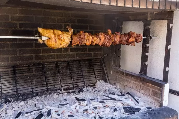 Ein Drehspieß über einer Feuerstelle mit diversen Fleischsorten im griechischen Stil in Chalkio, Naxos