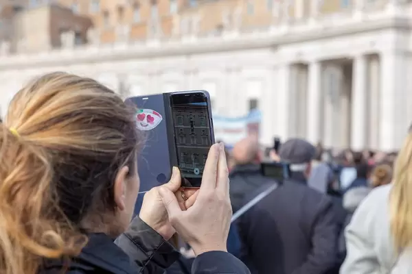 Ein Frau macht ein Foto mit dem iPhone auf dem Peterdplatz im Vatikan