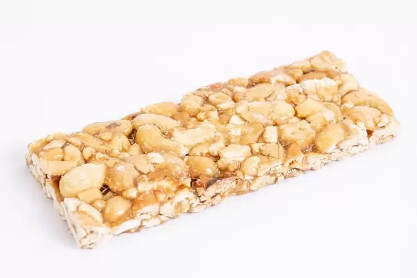 Ein ganzer Cashew-Müsliriegel liegt isoliert vor weißem Hintergrund