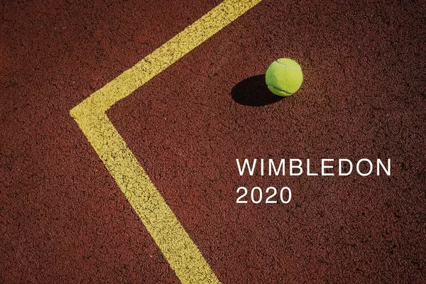 Ein gelber Tennisball liegt auf dem Tennistunierplatz, neben der Aufschrift "Wimbledon 2020"