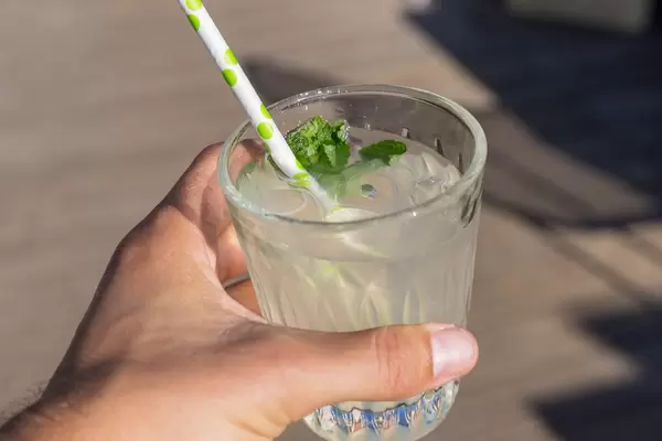 Ein Glas Limonade mit Minze und Eis in der Hand