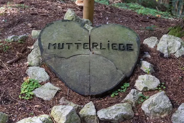 Ein großes Herz aus Holz mit der Schrift "Mutterliebe" auf dem Boden im Wald in Alpbach