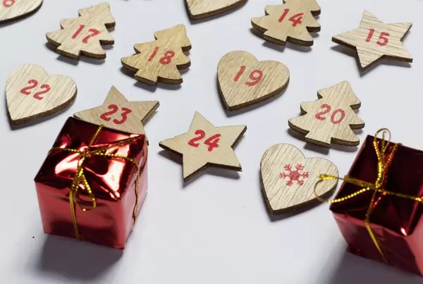 Ein hölzener Adventskalender mit kleinen Weihnachtsgeschenken auf weißem Hintergrund