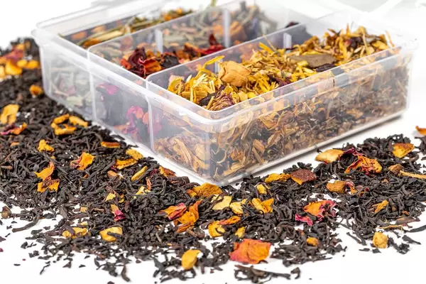 Ein Kasten mit unterschiedlichen Teesorten und gestreutem Trockentee auf weißem Hintergrund