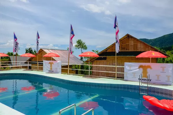 Ein kleiner Swimmingpool mit roten Sonnenschirmen in Kampo Hiyang