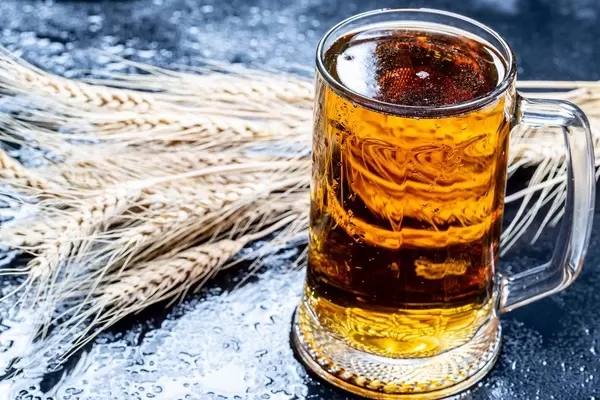 Ein Krug Bier mit Weizenähren auf schwarzem Hintergrund