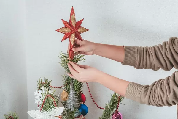 Ein Mädchen steckt den Stern auf die Weihnachtsbaumspitze