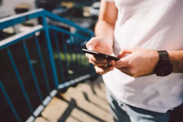 Ein Mann in weißem T-Shirt bedient sein Smartphone