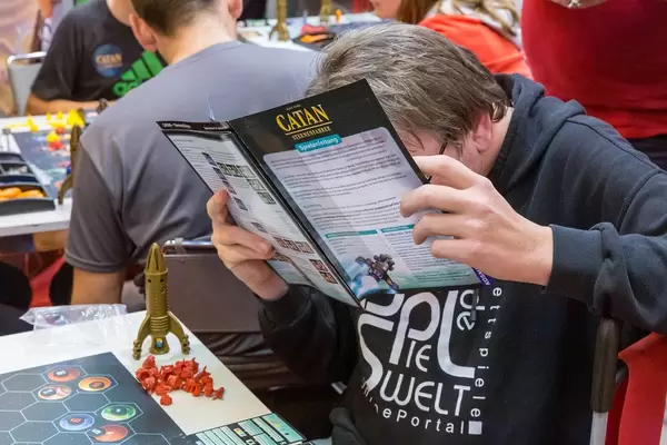 Ein Mann liest sich die Catan Sternenfahrer Spielanleitung durch