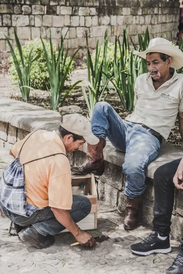 Ein Mann poliert die Schuhe eines Cowboys