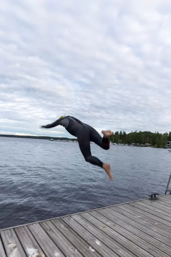 Ein Mann springt in einen See bei Padasjoki, Finnland, während er einen Taucheranzug trägt