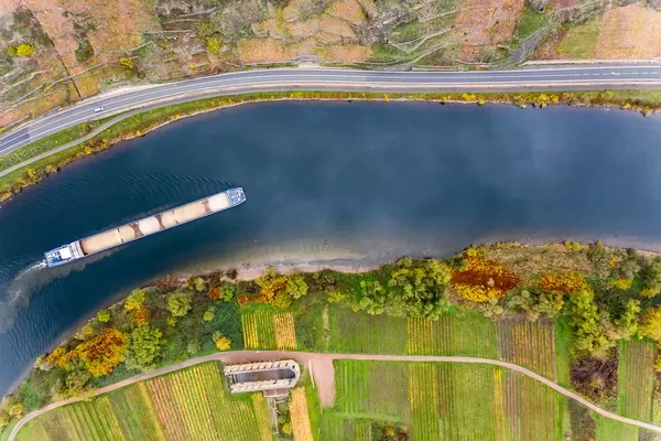 Ein mit Sand beladenes Frachtschiff fährt auf der Mosel vorbei an Kloster Stuben und Weinbergen am Berg Calmont in Bremm, Deutschland Luftaufnahme