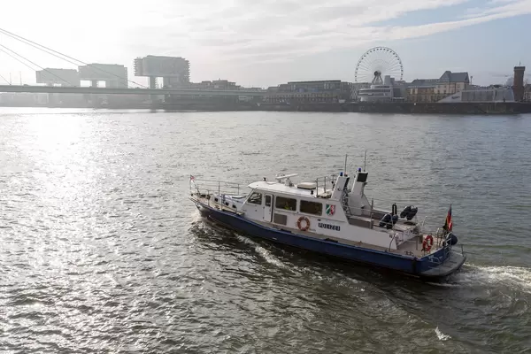 Ein Polizeiboot am Rhein in Köln mit Riesenrad und Kranhäusern im Hintergrund